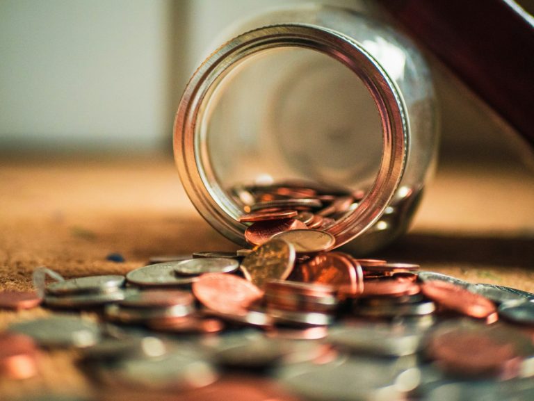 A glass jar tipped over with coins spilling out — symbolizing saving money and financial planning in Canada.