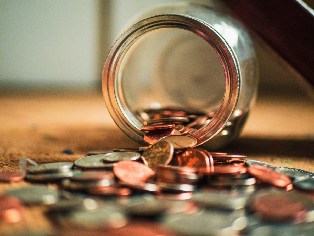 A glass jar tipped over with coins spilling out — symbolizing saving money and financial planning in Canada.