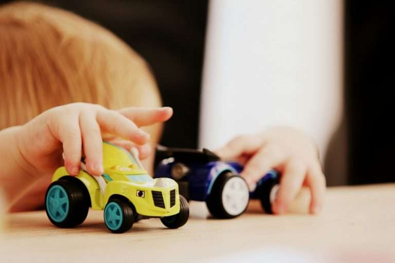 A baby playing with two toy cars that fit the Baby Gear Budget in Canada.