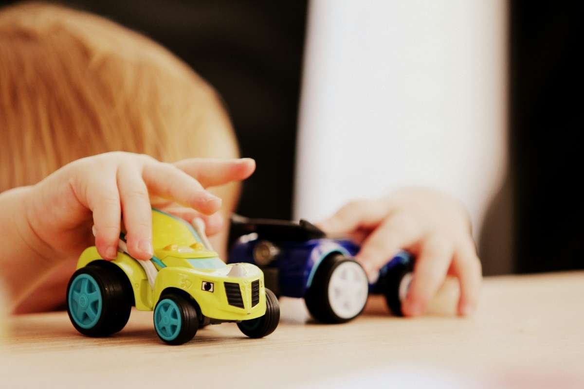 A baby playing with two toy cars that fit the Baby Gear Budget in Canada.